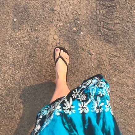 karen's leg in a blue skirt walking on sand