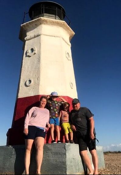 Karen's family on holiday in front of a lighthouse