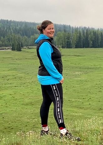 Karen smiling and standing in a mountain field wearing ZYIA 