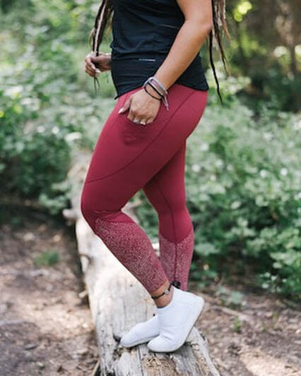 female model in a forest wearing red ZYIA leggings